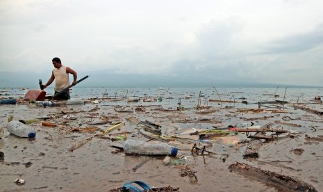 Seorang warga mengambil barang bekas yang sekiranya masih layak dimanfaatkan di pesisir objek wisata pantai Kalaki, Desa Panda, Kecamatan Palibelo, Kabupaten Bima, Nusa Tenggara Barat, Sabtu (24/12).