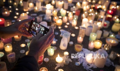  Seorang warga mengambil gambar lilin untuk mengenang korban penembakan di luar Masjid Al Noor di Christchurch, Selandia Baru, Senin (18/3/2019).