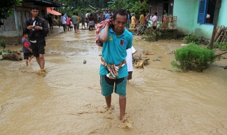 Seorang warga mengangkat barang-barang yang masih bisa diselamatkan untuk mengungsi, akibat banjir bandang di Jorong Kampuang Padang Paraman Dareh, Nagari Air Manggis, Kecamatan Lubuak Sikapiang, Kabupaten Pasaman, Sumatera Barat, Rabu (16/12).