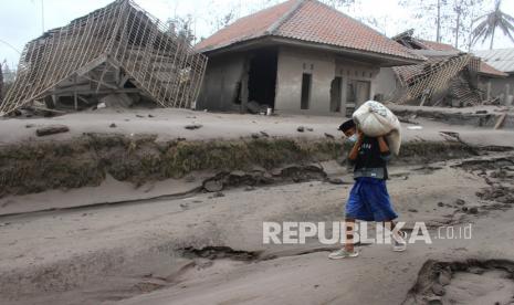 Seorang warga mengangkut barang yang bisa diselamatkan dari rumahnya yang hancur akibat erupsi gunung Semeru yang meluncurkan awan panas di desa Supiturang, Lumajang, Jawa Timur, Ahad (5/12/2021). Luncuran awan panas akibat letusan gunung Semeru mengakibatkan puluhan rumah di dua kecamatan rusak dan delapan kecamatan terdampak abu vulkanik. 