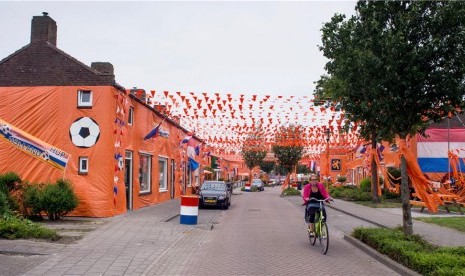 Seorang warga mengendarai sepeda di Goirle, Belanda, yang dihiasi dengan bendera, atribut, dan warna khas timnas Belanda. 