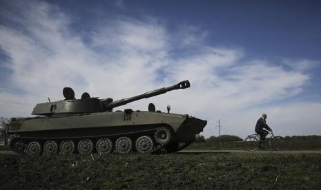 Seorang warga mengendarai sepeda melewati tank howitzer Ukraina, di Kharkiv, Ukraina, 7 Mei 2022.