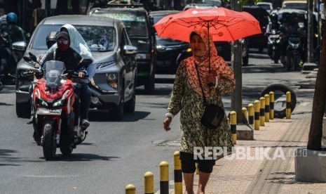 Seorang warga menggunakan payung saat cuaca terik di jalur pedestrian Jalan Juanda, Kota Bekasi, Jawa Barat, Selasa (22/10/2019).