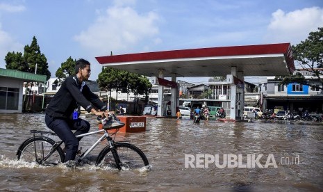 Seorang warga menggunakan sepeda melintasi genangan banjir di Jalan Raya Andir, Baleendah, Kabupaten Bandung, Jumat (24/1).