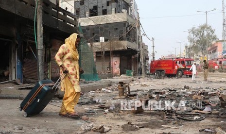 Seorang warga meninggalkan lingkungan rumahnya yang hangus saat bentrok massa pendukung dan penentang UU Kewarganegaraan India berujung rusuh di New Delhi, India. PM India Narendra Modi minta masyarakat jaga perdamaian dan persaudaraan.