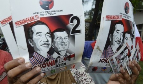 Seorang warga menunjukkan poster bergambar Joko Widodo - Jusuf Kalla di kawasan Pelabuhan Perikanan Pantai Tegalsari, Tegal, Jawa Tengah, Kamis (19/6). 