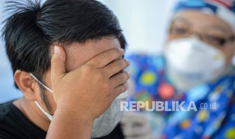 Seorang warga menutup matanya saat mendapatkan suntikkan vaksinasi COVID-19 dosis kedua dalam 