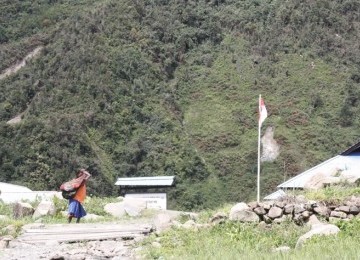 Seorang warga Mulia, Puncak Jaya, membawa hasil kebunnya dengan Noken di punggung, melewati jalan setapak di depan kampus Akademi Keperawatan Distrik Mulia.