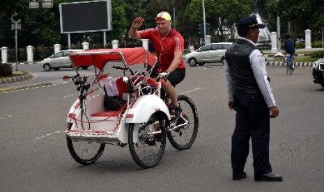 Seorang warga negara asing mengendarai becak melintasi Jalan Medan Merdeka Barat, Jakarta Pusat, Ahad (18/1).