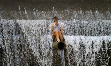 Seorang warga Pakistan mendinginkan diri di sungai di Islamabad.