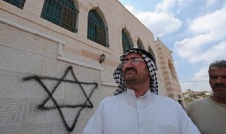 Seorang warga Palestina berdiri di depan masjid yang menjadi korban vandalisme Yahudi, di Nablus, Tepi Barat.