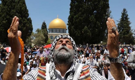 Seorang warga Palestina berdoa di kompleks Masjid Al-Aqsha dengan latar belakang Masjid Qubbah AS-Shakhrah (Masjid Dome of Rock)..