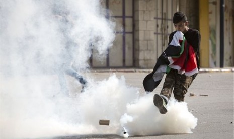 Seorang warga Palestina menendang gas air mata ke arah tentara Israel dalam kerusuhan di kompleks Masjid Al-Aqsa, Selasa (15/9). 