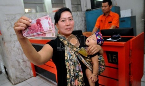  Seorang warga pemegang kartu perlindungan sosial (KPS) Bantuan Langsung Sementara Masyarakat (BLSM) di Kantor Pos Jatinegara, Jakarta Timur, Senin (2/9).   (Republika/Prayogi)