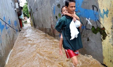  Seorang warga sambil menggendong anaknya melintasi banjir di Jalan Kampung Melayu Kecil, Kelurahan Bukit Duri, Kecamatan Tebet, Jakarta, Selasa ( 5/3).  (Republika/Prayogi)