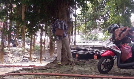 Seorang warga sedang buang air kecil di bawah pohon di daerah Galur, Jakarta Pusat.