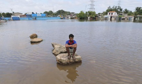 Seorang warga Sri Lanka duduk di potongan beton di wilayahnya yang terendam banjir di Kolombo, Sri Lanka, Ahad, 22 Mei 2016.