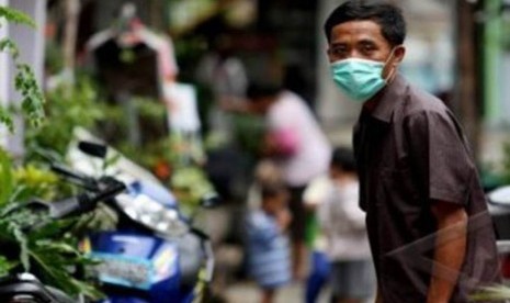 Seorang warga Sunter memakai masker setelah seorang pemuda berinisial PDY meninggal dunia akibat terjangkit flu burung di Sunter Agung, Tanjung Priok, Jakarta Utara, Senin (9/1). 