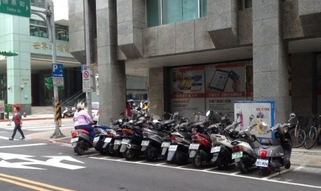 Seorang warga Taipei menyeberang di zebra cross, seorang lainnya memarkir motor dengan tertib di tempat yang telah disediakan.