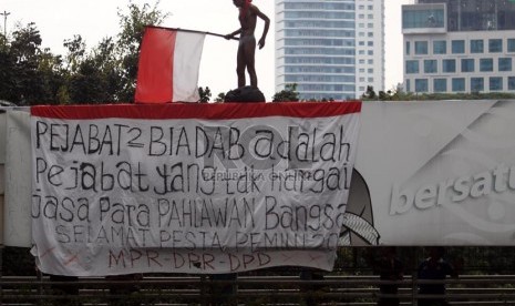  Seorang warga tidak dikenal nekat menaiki JPO dengan mengibarkan bendara dan spanduk protes di kawasan Dukuh Atas, Jakarta Pusat, Rabu (11/12).     (Republika/Adhi Wicaksono)