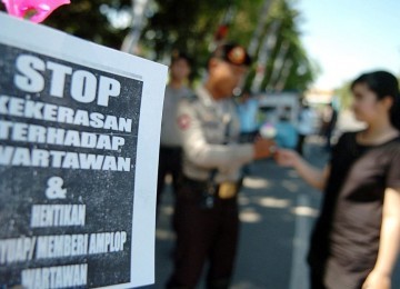 Seorang wartawan membagi-bagikan bunga kepada aparat kepolisian saat melakukan aksi bersama puluhan wartawan lainnya dalam rangka memperingati Hari Pers se-Dunia di Monumen Mandala Makassar, Sabtu (3/5). Dalam aksinya, mereka menuntut dihentikan segala ben