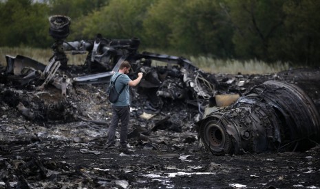 Seorang wartawan mengambil gambar sisa-sisa pesawat Malaysia Airlines MH17, Jumat (18/7)