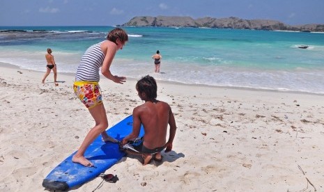 Seorang wisatawan asal Australia belajar tehnik bermain surfing di Pantai Tanjung Aan, Desa Kuta, Kec. Pujut, Praya, Lombok Tengah, NTB, Senin (15/10).