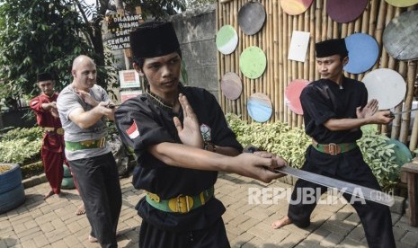 Seorang wisatawan mancanegara (kedua kiri) berlatih Pencak Silat Golok Terbang di Situ Rawa Gede, Bekasi, Jawa Barat, Ahad (8/9/2019).