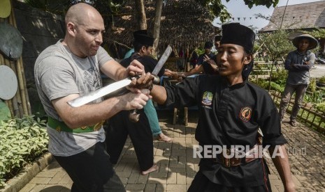 Silat Indonesia tidak sebatas seni bela diri. Seorang wisatawan mancanegara (kiri) berlatih Pencak Silat Golok Terbang di Situ Rawa Gede, Bekasi, Jawa Barat (ilustrasi).