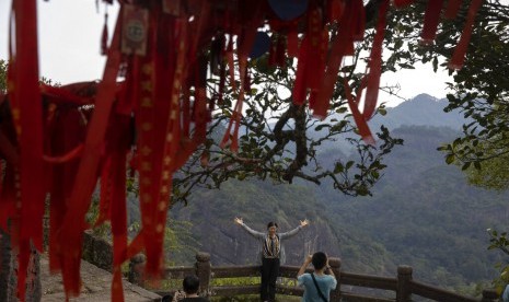 Seorang wisatawan mengambil foto di Puncak Tianoyou di Wuyishan, Provinsi Fujian, Cina, Rabu (14/8). Aktivitas sektor jasa di Cina meningkat ke level tertinggi sejak tujuh bulan terakhir pada November.