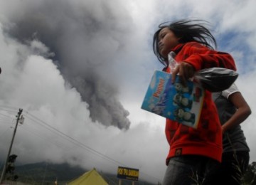 Seorang anak berlari menyelamatkan diri saat terjadi semburan material vulkanik dari puncak Gunung Merapi yang tertutup kabut, dari Tempat Pengungsian Akhir Samiran, Selo, Boyolali, Jateng