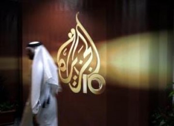 Seorang karyawan stasiun televisi Arab Al Jazeera berjalan melewati logo Al Jazeera di Doha, Qatar. FIFA memperpanjang hak siaran Al Jazeera hingga Piala Dunia 2022.