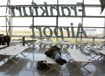 Seorang penumpang tertidur di bandara Frankfurt, Jerman. Belum ada kepastian kapan penerbangan di bandara itu akan dilakukan.