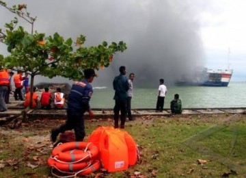 Seorang petugas pemadam kebakaran menyusun selang air untuk memadamkan Kapal Roro Lautan Teduh yang terbakar di Selat Sunda, Merak, banten, Jumat (28/1). 