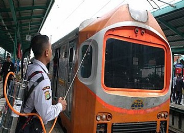  Seorang petugas PT. Kereta Api Indonesia ( PT. KAI), mengenakan alat penyemprot penumpang yang duduk di atas gerbong saat uji coba, di Stasiun Manggarai, Jakarta