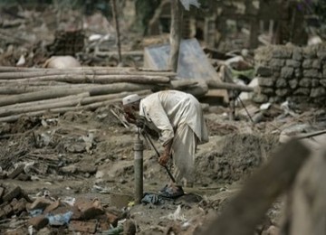 Seorang pria Pakistan berwudhu di keran air yang tersisa dari banjir yang menyapu wilayahnya