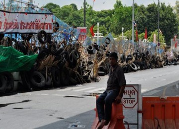 Seorang warga Bangkok duduk di sisa-sisa barikade Kaus Merah yang belum dibersihkan.