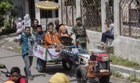 Sepasang pengantin diarak dengan traktor dalam acara Nikah Bareng Jogja Istimewa di Alas Kradenan, Piyungan, Bantul, Yogyakarta, Sabtu (28/3).