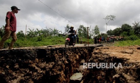 Sepeda motor melintas di jalan yang terbelah akibat pergerakan tanah di jalur wisata, Karang Tengah, Sentul, Kabupaten Bogor, Jawa Barat, Sabtu (16/2/2019).