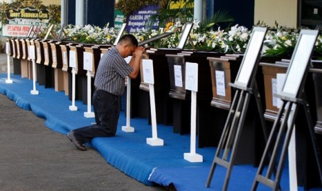 SERAH TERIMA JENAZAH. Seorang keluarga korban berdoa di depan peti jenazah korban kecelakaan pesawat Sukhoi Super Jet 100 yang disemayamkan sebelum acara serah terima jenazah di Bandara Halim Perdanakusuma, Jakarta, Rabu (23/5).