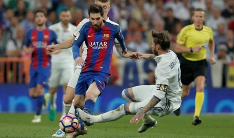 Sergio Ramos (kanan) saat hendak menekel Lionel Messi.