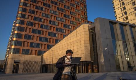 Seseorang bekerja di depan laptop miliknya di sebuah ruamg terbuka di Beijing, China.