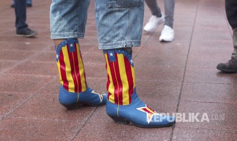 Seseorang memakai sepatu bot dengan warna bendera Catalonia di Barcelona,  Spanyol, (1/10).   