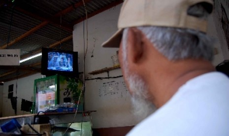 Seseorang menyaksikan televisi di sebuah warung.