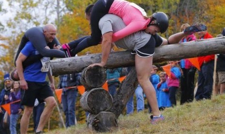 Shane Arnold and Brandy Bates clear the second obstacle ahead of Ian and Susan Bell (left) while competing in the North American Wife Carrying Championship at Sunday River ski resort in Newry, Maine October 11, 2014.  