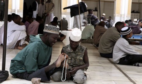   Sharif Ismail menunjukkan cara ia menggunakan tasbih pada seorang anak laki-laki saat menunggu ibadah shalat Jumat di masjid Jami kota Nairobi, Kenya Jumat (10/8). (Noor Khamis/Reuters)