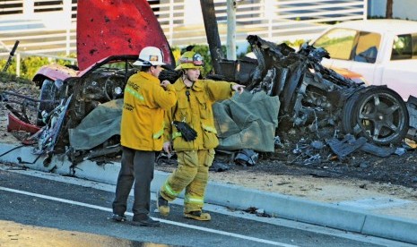 Sheriff's deputies work near the wreckage of a Porsche that crashed into a light pole on Hercules Street near Kelly Johnson Parkway in Valencia, Calif., on Saturday, Nov. 30, 2013. 