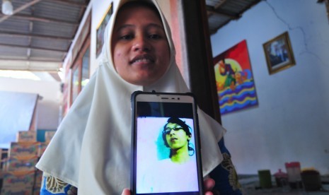 Sianit Sinta menujukkan foto mendiang suaminya Ahmad Budi Cahyanto guru SMAN 1 Torjun yang tewas dipukul siswanya sendiri, di Desa Tanggumung, Sampang, Jawa Timur, Sabtu (3/2).