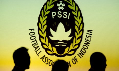 Siluet sejumlah orang di depan logo PSSI.