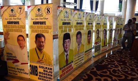 Simpatisan salah satu calon ketua umum Golkar melintas di samping banner calon ketua umum Golkar saat kampanye calon ketua umum Golkar zona II di Surabaya, Jawa Timur, Rabu (11/5).